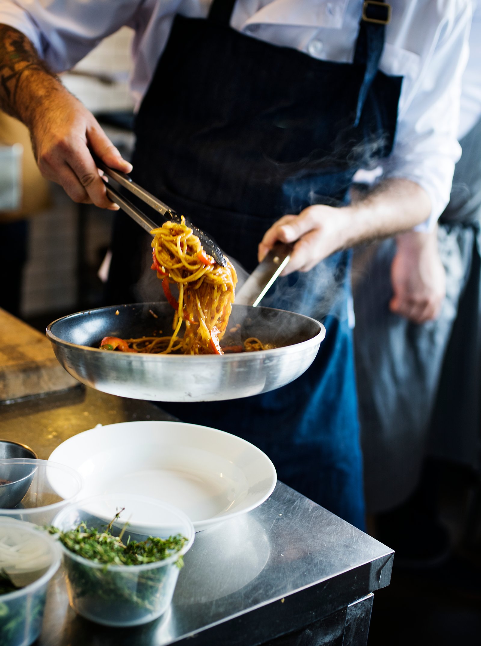 Chef cooking spaghetti in kitchen